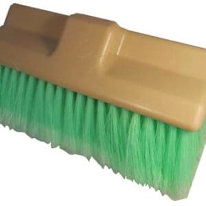 A green and tan brush is sitting on the floor.