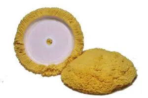 A yellow sponge is next to a white disc.