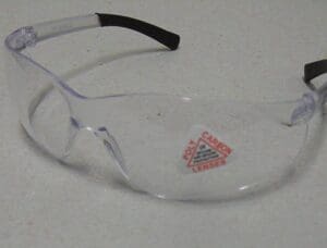 A pair of clear safety glasses with a red triangle on the side.